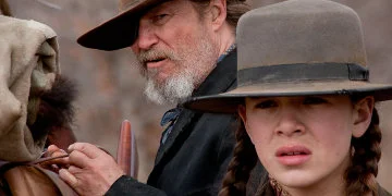 Rooster Cogburn Tying Up His Bag Stood Next To Mattie Ross